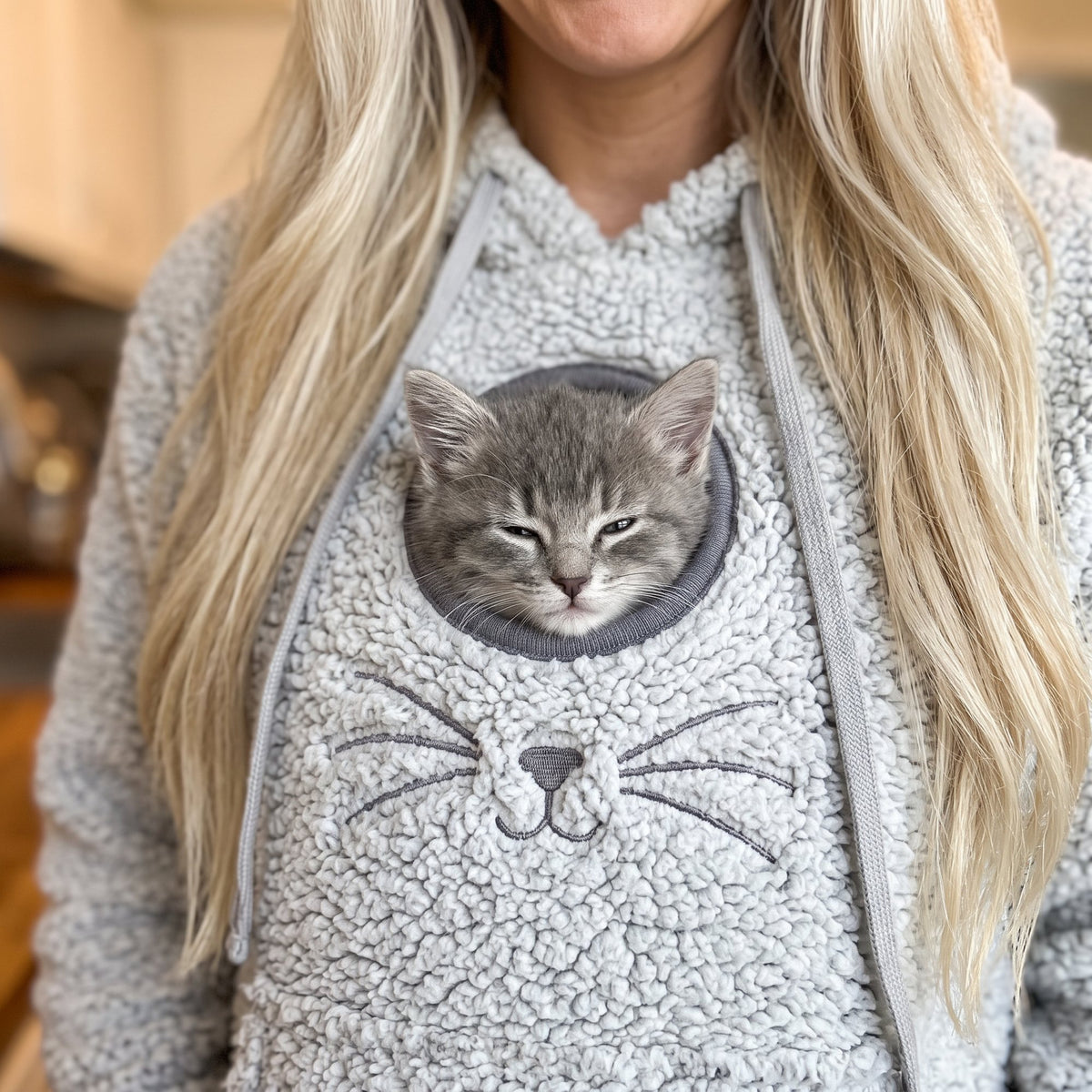 Kitten peeking out of a grey pouch hoodie